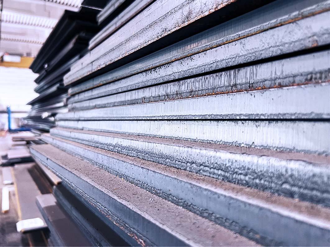 Gestapelte, leicht oxidierte Metallplatten in einer Industriehalle aus der Nähe.